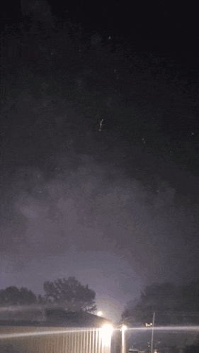 a dark night sky with a few stars and a house in the foreground