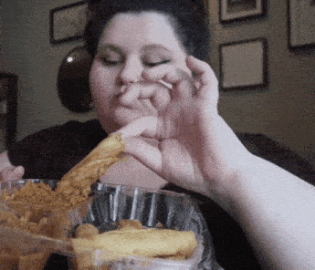 a woman eating chicken and french fries in a plastic container