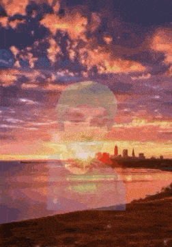 a sunset over a body of water with a silhouette of a person in the foreground
