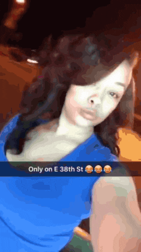a woman in a blue shirt is taking a selfie with the words only on e 38th st