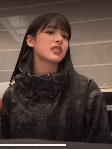 a woman wearing a black jacket with the letter b on it is sticking out her tongue .