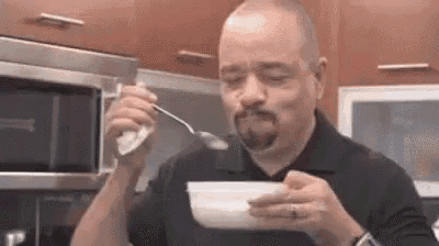 a man is eating a bowl of cereal with a spoon in his mouth .