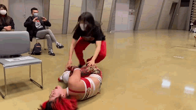 a woman wearing a mask is kneeling over a wrestler