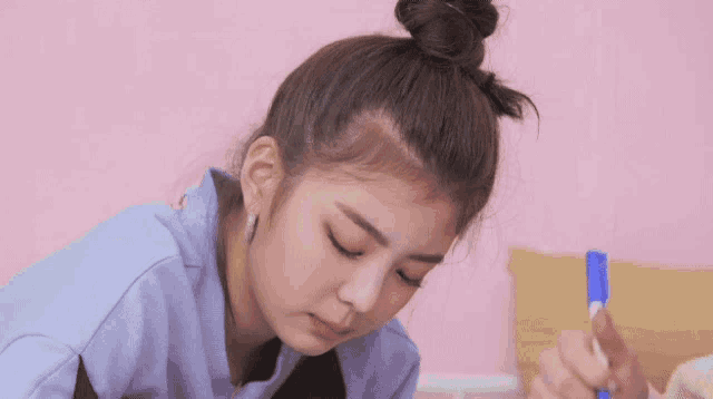 a young girl is sitting on a bed with a bun on her head and a marker in her hand .