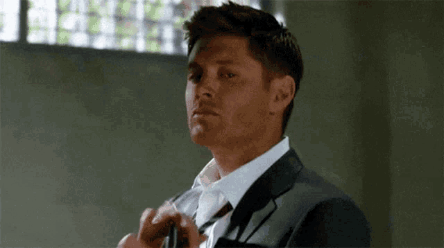 a man in a suit is adjusting his tie .