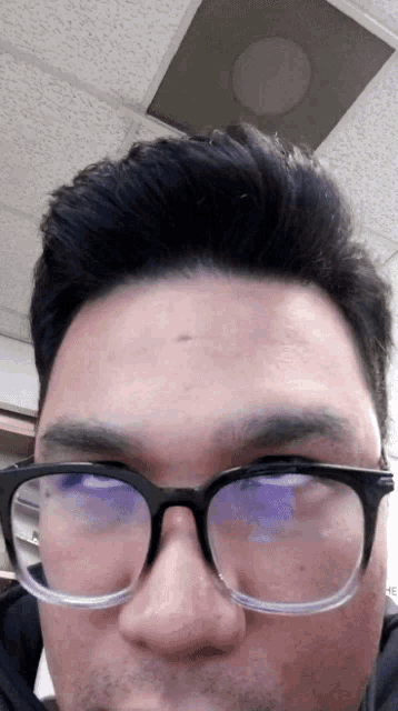 a close up of a man wearing glasses and a black shirt