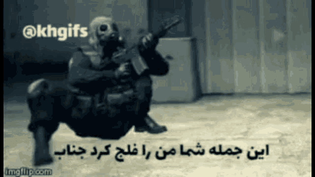 a man in a gas mask is holding a gun while sitting on the ground .