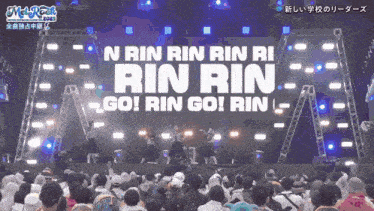 a crowd of people watching a concert with the words rin rin go on the screen