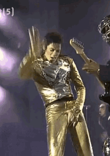 a man in gold pants is playing a guitar with the number 15 on the bottom right