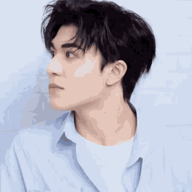 a young man wearing a blue shirt and white t-shirt is looking to the side .