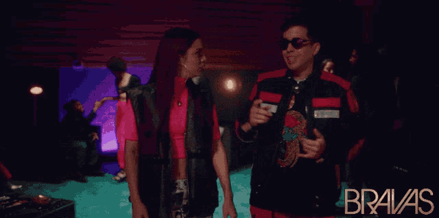 a man and a woman are standing next to each other in a room with the word bravas on the bottom