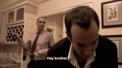 a man in a suit and tie is standing next to another man in a kitchen and talking to him .
