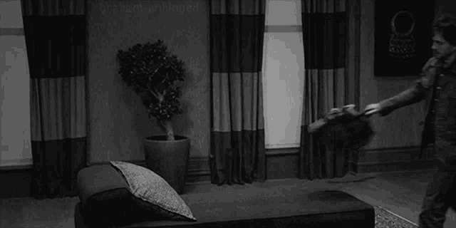 a black and white photo of a man fighting another man in a living room .