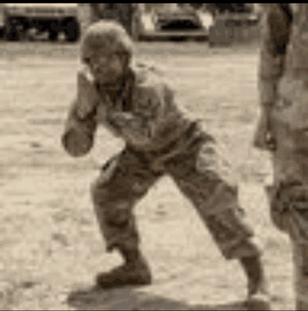 a man in a military uniform is standing in the dirt .