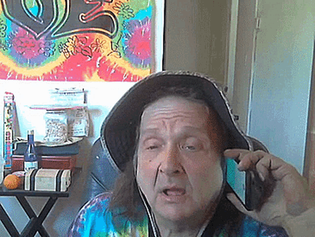 a woman wearing a tie dye shirt and a hooded hat