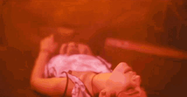 a woman is laying on the floor in a dark room with red lights .