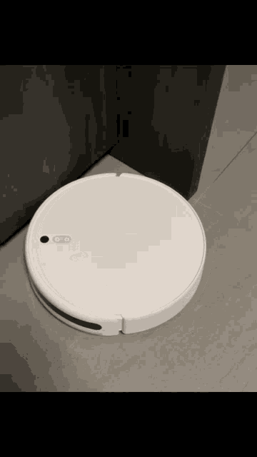 a white robot vacuum cleaner is sitting on a tiled floor next to a door