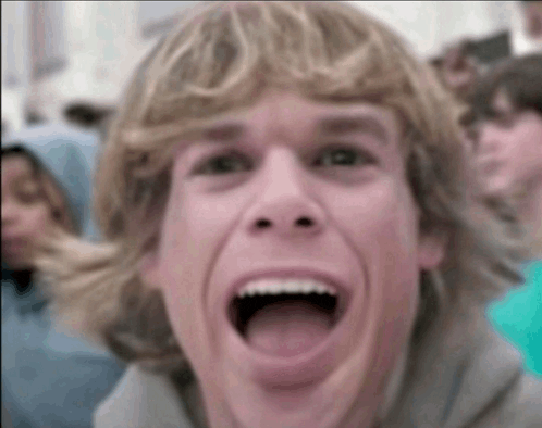 a young man with blonde hair is making a funny face with his mouth open