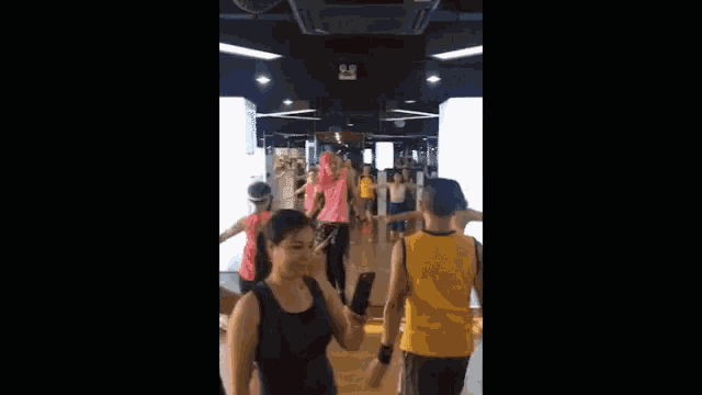 a group of people are dancing in a gym with a sign that says pink danny .