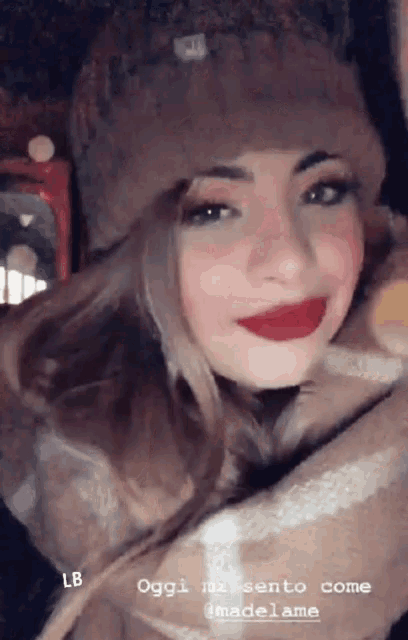 a woman wearing a hat and a scarf is smiling for the camera .