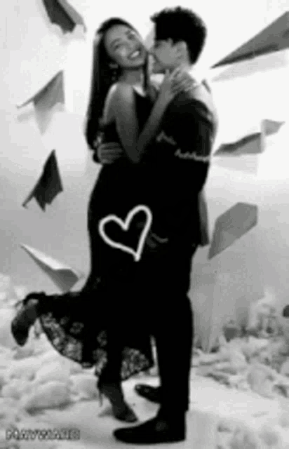 a black and white photo of a man holding a woman with a heart drawn on it