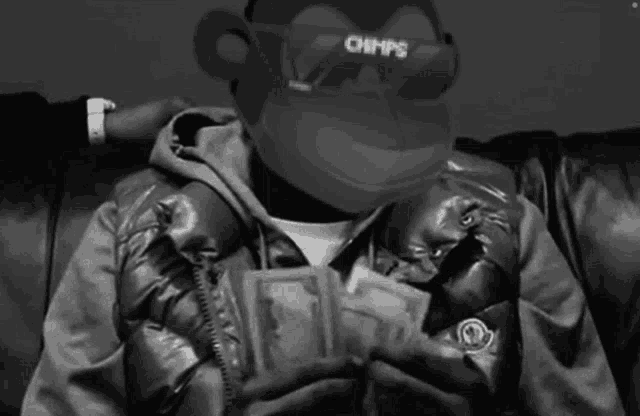 a man is sitting on a couch holding a bunch of money .