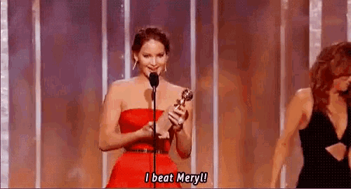 a woman in a red dress is holding a trophy and speaking into a microphone on a stage .
