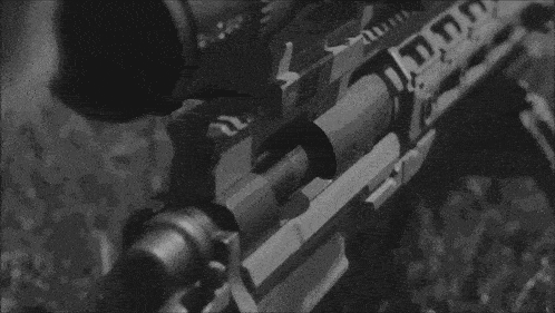 a black and white photo of a person holding a rifle in their hand .