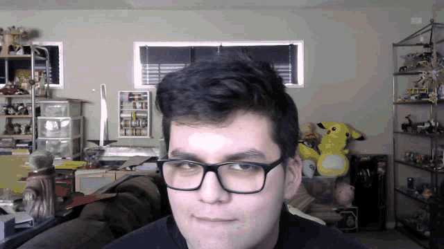 a man wearing glasses looks at the camera in a room full of toys
