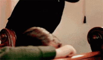 a person is sitting on a chair with their legs crossed and their hands on a table .