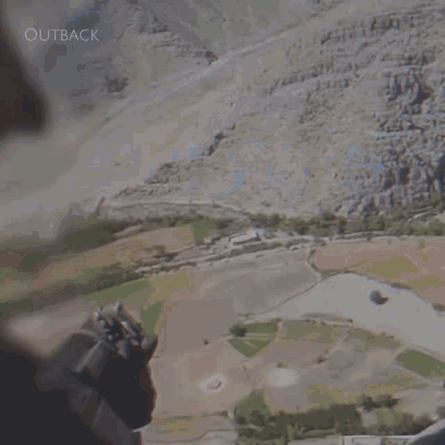 a soldier is walking down a dirt road with outback written on the bottom right