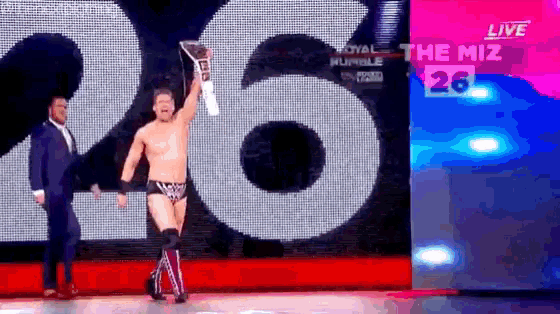 a man holding a trophy in front of a sign that says miz 26