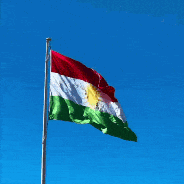 a red white and green flag is flying in a blue sky
