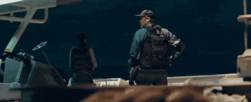 a man in a captain america costume is holding a shield while standing on a boat .
