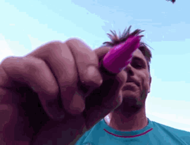 a man wearing a blue shirt is holding a pink object in his hand