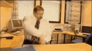 a man in a white shirt and tie is standing in front of a computer