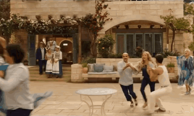 a group of people are dancing in front of a building in a movie .