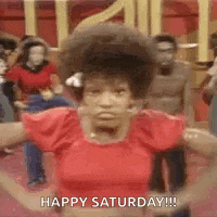 a woman in a red shirt is dancing in front of a group of people and saying happy saturday .