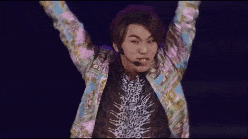 a man wearing a microphone and a colorful jacket is dancing on stage .