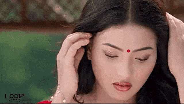 a close up of a woman 's face with a red bindi on her forehead .