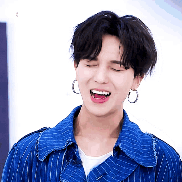 a young man wearing hoop earrings and a blue striped jacket