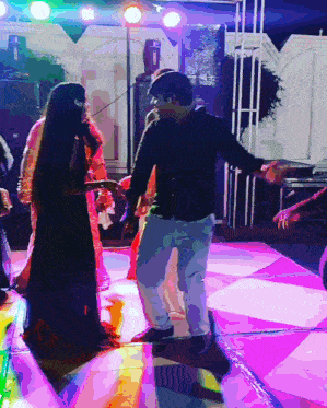 a man and a woman are dancing on a pink dance floor