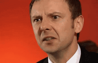 a man in a suit and tie is making a funny face with his mouth open .
