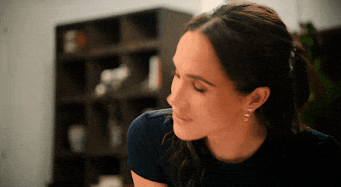 a woman wearing a blue shirt and earrings is looking down
