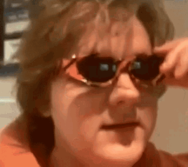 a woman is wearing sunglasses and making a face .