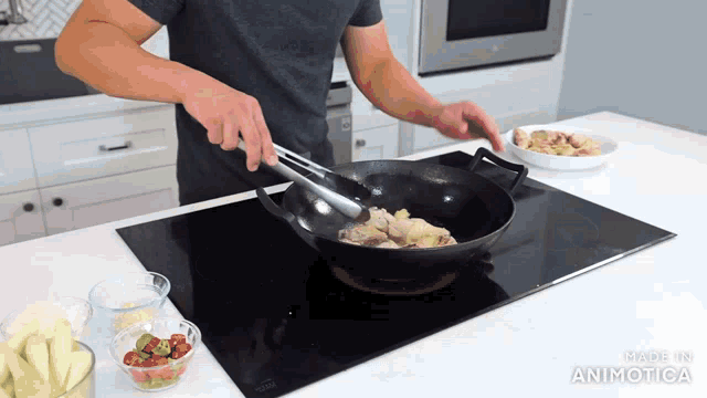 a man is stirring food in a wok on a stove with the words made in animatica below him