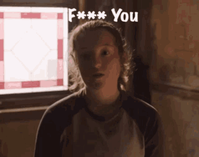 a girl is standing in front of a window and the words f *** you are above her