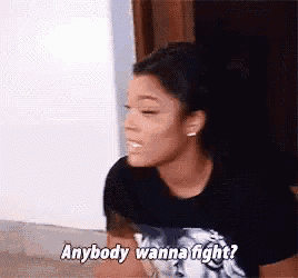 a woman in a black shirt is talking to another woman and says `` anybody wanna fight ? ''