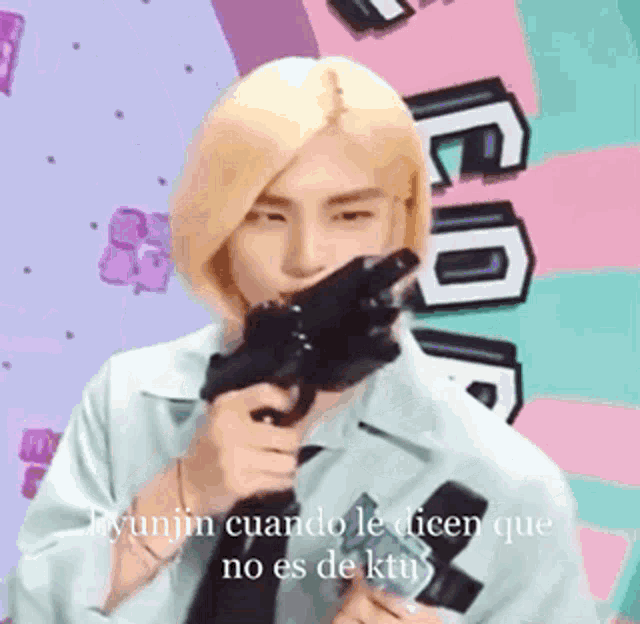 a man with blonde hair is holding a gun in his mouth and says hyunjin cuando le dicen que no es de ktu