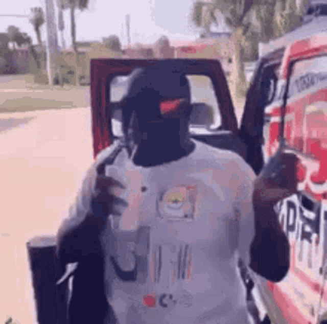 a man in a white shirt and black hat is standing next to a red truck .